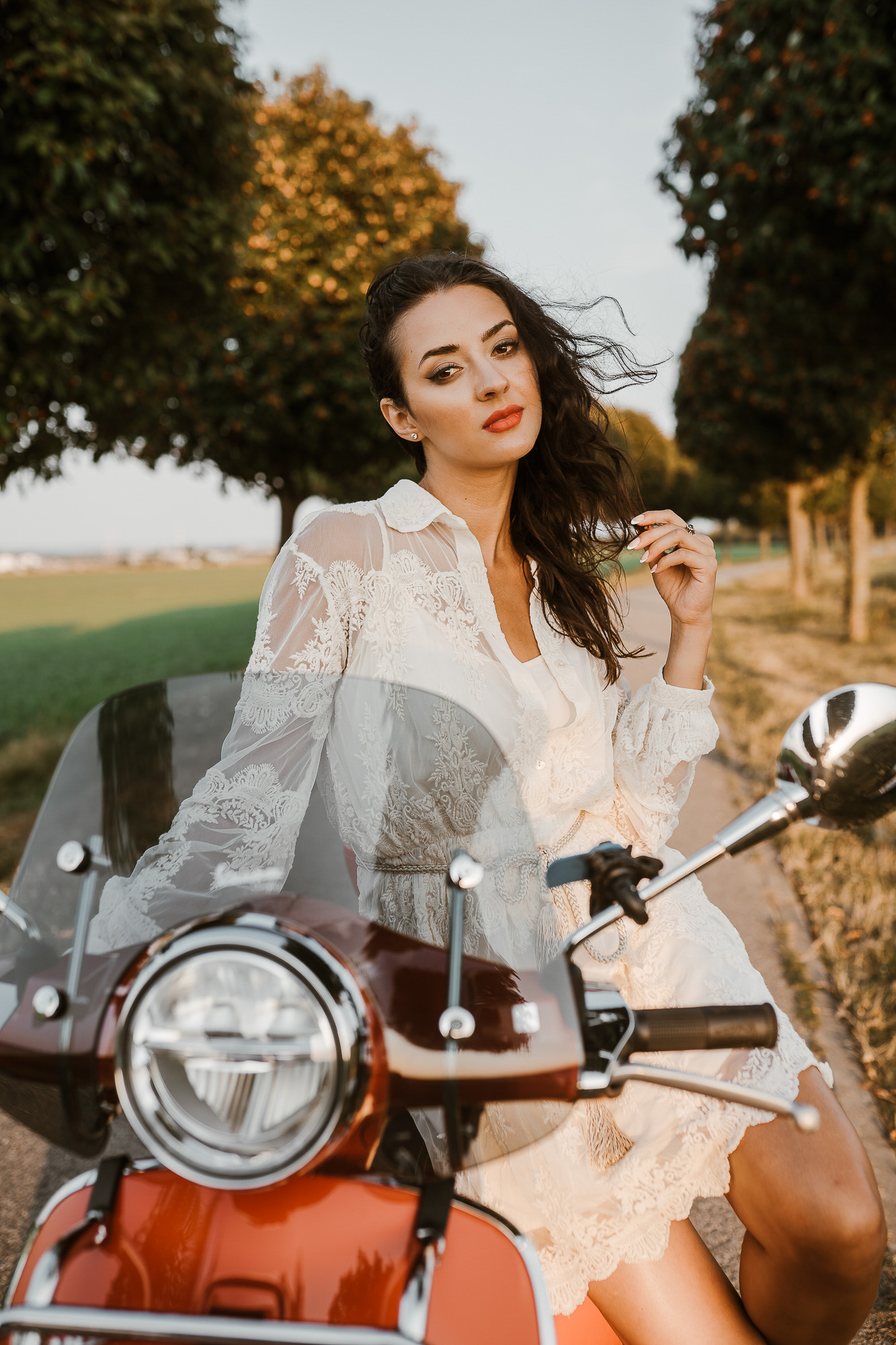 Žena v bílých šatech sedí na motorce